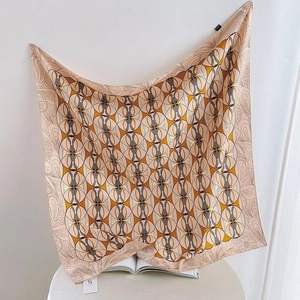 Detailed view of geometric circle print and paisley pattern on a beige silk scarf