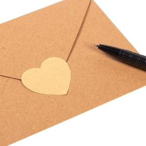 Close-up of heart-shaped kraft paper sticker on envelope with a black pen on the side