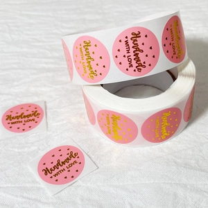 Pink round stickers on a roll featuring gold foil Handmade with Love and heart patterns