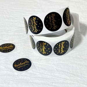 Macro view of round black stickers with gold foil Handmade with Love text on roll