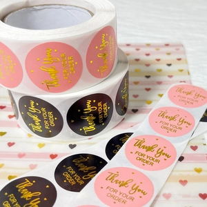 Gold foil Thank You stickers in pink and black rolls for wedding gift packaging