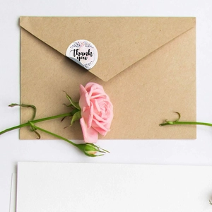 Close-up of floral Thank You sticker seal on a kraft envelope with a pink rose decoration