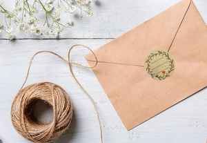 Detail of round kraft paper seal sticker with floral wreath and heart on brown envelope