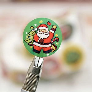 Green Christmas sticker with Santa and tree pattern shown on a metal cutter tip