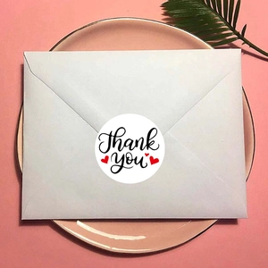 White circular Thank You sticker with red heart used as a seal on a white envelope