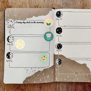 DIY grid planner notebook with cute cartoon stickers on a dark wood grain desk