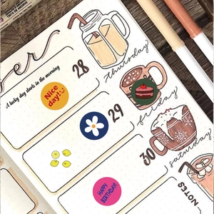 Detail of round cartoon planner stickers on a journal page with decorative floral motifs