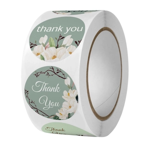 Macro detail of round floral stickers with white magnolia and Thank You text on roll