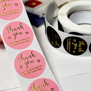 Macro detail of round pink and gold foil Thank You stickers with metallic glossy finish