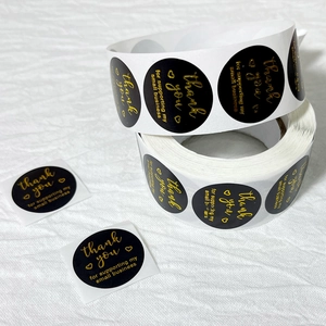 Detail of round black thank you stickers with gold foil text for small business packaging