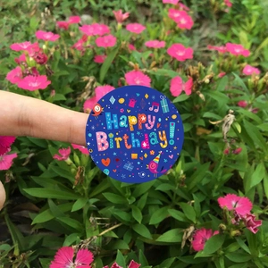 Round happy birthday stickers with festive icons held against a floral background
