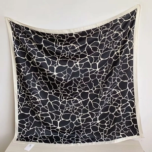 Black and white abstract stone pattern square silk scarf with white border hanging on wall