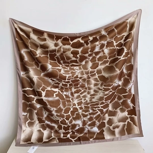 Détail d'un foulard en satin à motif girafe avec bordures cousues marron café