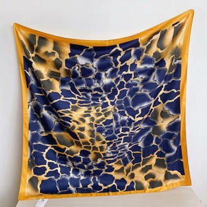 Détail du foulard carré en soie avec texture d'imprimé géométrique bleu marine et jaune