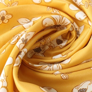 Macro view of bright yellow floral silk scarf showing elegant twill weave texture
