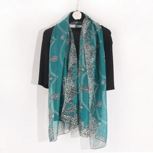 Detail of teal chiffon scarf featuring gold chain and leopard print draped on a hanger