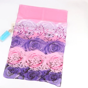 Close-up of pink floral chiffon scarf with rose patterns and perfume bottle