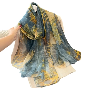 Châle en soie imprimé bleu et jaune avec motifs de feuilles et broche camélia élégante