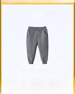 Détail du jogging gris pour enfant avec broderie dinosaure orange et finitions côtelées