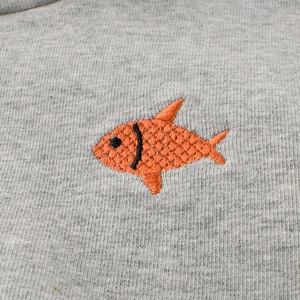 Gros plan sur un t-shirt enfant gris chiné à manches longues avec broderie poisson orange