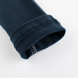 Detail of dark blue knit sleeve cuff showing precise overlock stitching and cotton texture