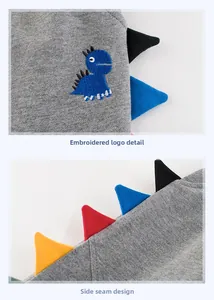 Dettaglio dei pantaloni grigi per bambini con ricamo a dinosauro e punte colorate