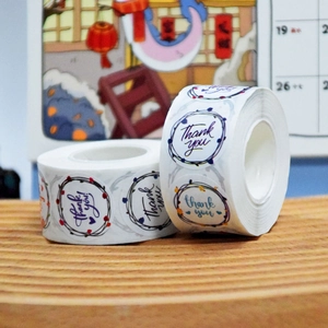 Detailed close-up of decorative floral Thank You roll stickers on a wooden surface