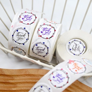 Detail view of colorful floral wreath 'Thank You' stickers in a rustic packaging setting