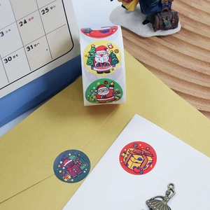Close-up of circular Christmas stickers featuring Santa and tree on a gift envelope
