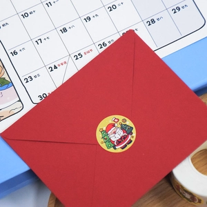 Red festive envelope sealed with a cartoon Santa Claus and Christmas tree sticker