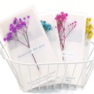 Minimalist handmade gift cards with colorful dried flowers in a white mesh basket