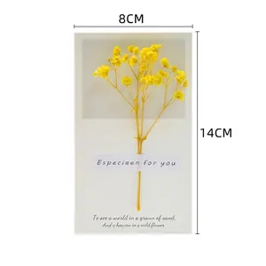 Detail of creative handmade gift card featuring dried yellow flowers on premium paper