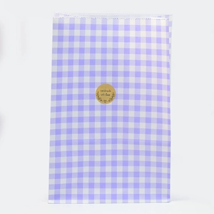 Detail der lila-weiß karierten Geschenktüte aus Papier mit goldenem Aufkleber
