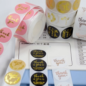 Macro shot of assorted round thank you stickers in pink and black with gold foil lettering