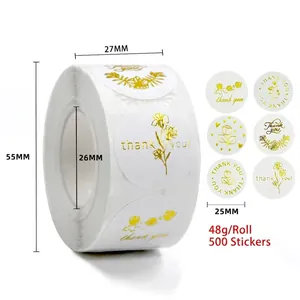 Macro detail of 25mm round gold foil thank you stickers with floral patterns on a white roll