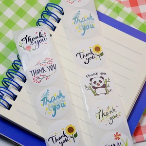 Minimalist white round Thank You stickers with floral and panda designs on a notebook
