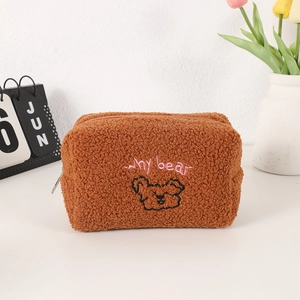 Detail of soft brown plush teddy fabric with cute bear embroidery and metal zipper