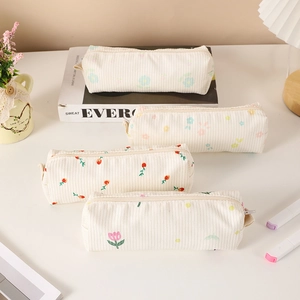 Detailed view of four floral corduroy pencil cases with zippers on a desk