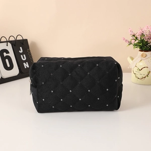 Detail of black quilted cosmetic bag with silver eyelets and smooth zipper closure