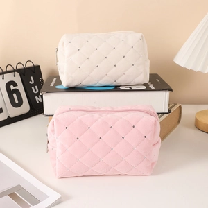 Detail of quilted velvet cosmetic bags with rhinestone accents in soft pink and white