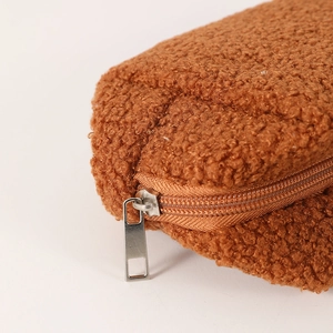 Close-up of brown teddy plush fabric texture and silver metal zipper on stationery bag