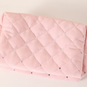 Macro shot of pink quilted plush fabric with sparkling silver sequins detailing