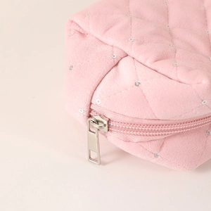 Macro view of pink quilted velvet makeup bag with zipper and silver sequin accents