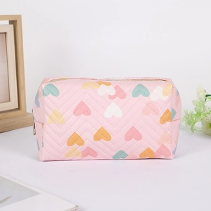 Close-up of quilted heart pattern and metallic zipper detail on a pink pencil case