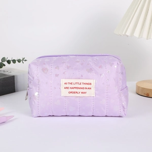 Close-up of quilted purple pencil case with heart patterns and white fabric label