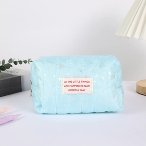 Sky blue quilted pencil case with silver hearts and slogan patch on a white desk