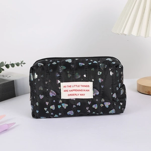 Detail view of black quilted pencil case with colorful heart prints and fabric label