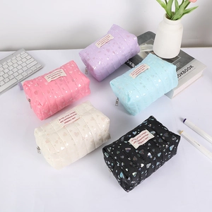 Quilted heart pattern pencil cases in five colors displayed with desk accessories