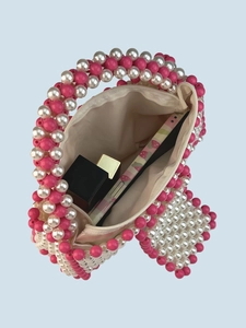 Sac en perles tissé main avec accents roses et fermeture éclair montré sous un angle de 45°