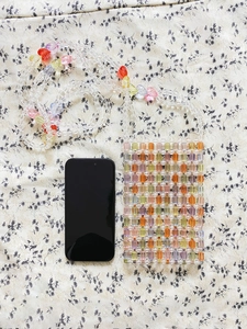 Handmade beaded crossbody phone bag with colorful acrylic heart beads and floral background